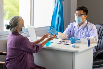 Asian doctor advised the old woman to wash her hands with alcohol before the treatment to prevent...