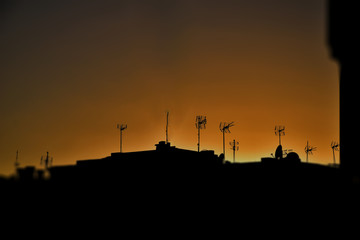  picturesque landscape at sunset with black roofs of houses and antennas