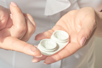 Cropped view of ophthalmologist holding contact lenses in hands. Woman Hands Holding White Eyelense Container. Eyesight and eyecare concept.