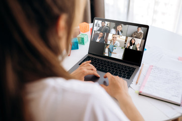Business team working from home in a video conference. The back view of a girl who communicates...