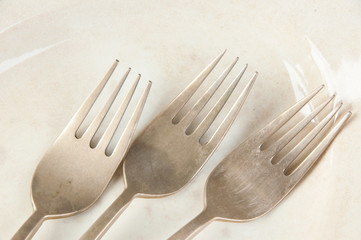 Three old bronze forks on concrete background.