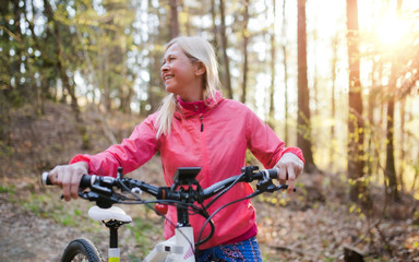 Fototapeta na wymiar Active senior woman with e-bike cycling outdoors in nature.