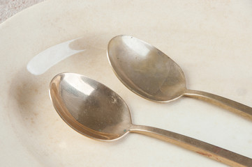Two old bronze spoons on concrete background.