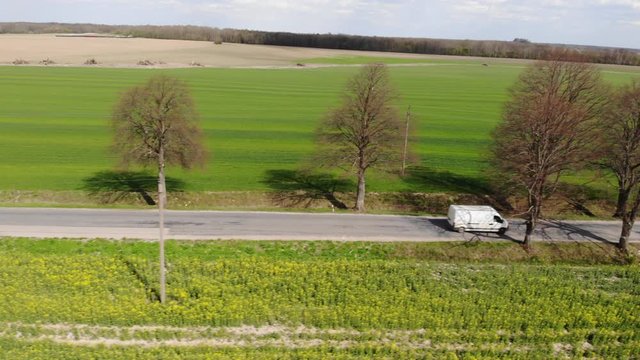 Delivery Van. Postal Delivery Service. Aerial View Shot of Car riding Through Empty Rural Road. Road on Countryside. Truck Driving Through Beautiful Suburban. Aerial View Spring Agricultural Fields.