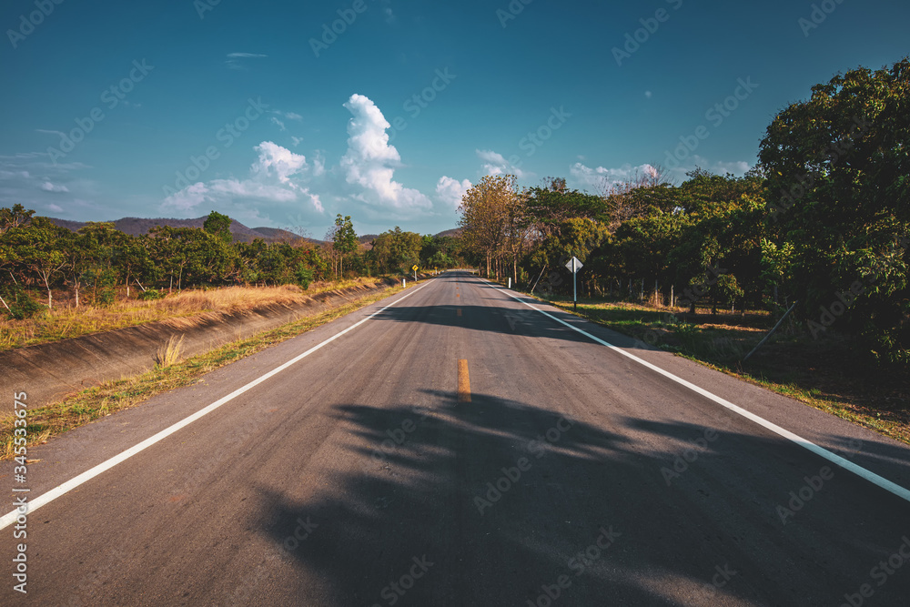 Sticker open road. Asphalt road through the green field and clouds on blue sky in summer day. 