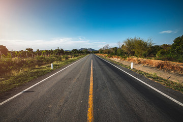 open road. Asphalt road through the green field and clouds on blue sky in summer day. 
