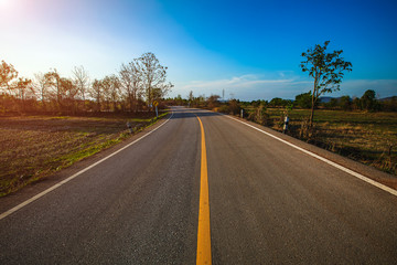Fototapeta premium open road. Asphalt road through the green field and clouds on blue sky in summer day. 