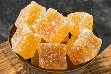 Orange marmalade in a brown bowl on a black background. Marmalade slices close up