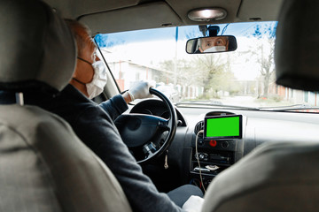 A man driving a car in a protective medical mask and gloves. Safe drive in a taxi during a pandemic coronavirus. Protect the driver and passengers from bacteria and virus infection in quarantine