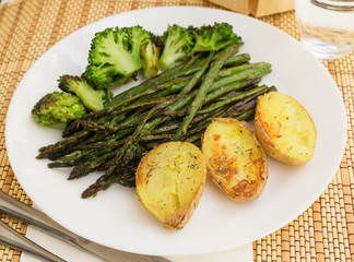 lean dish of cooked fried inflorescences of broccoli, asparagus growth and baked potatoes and Provencal herbs