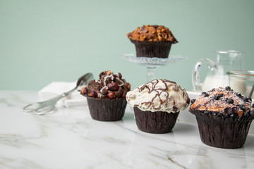 Muffin Auswahl mit Blaubeeren, Walnuss, Haselnuss und Weiße Schokolade mit Milch und Zucker für Kaffeepause auf Marmor Tisch und Grün Hintergrund