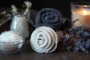 Beauty spa treatment and relax concept. Towel, sea salt and burning candle on a dark background