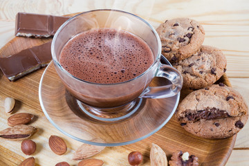 Hot chocolate, nuts and confections on wooden dish close-up