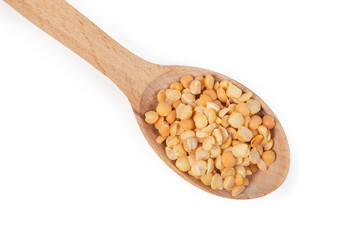 Uncooked yellow split peas in wooden spoon, top view closeup