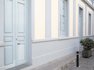 Old wooden door and shutters in vintage style on the gray wall with green bush. Street view of Puerto de la Cruz during Corona Virus pandemic. Puerto De La Cruz, Canary Islands, Spain - April 15, 2020