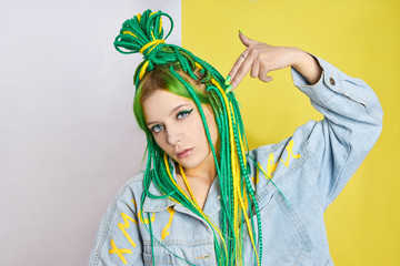 Portrait of a woman with creatively colored hair in green and yellow color. Colorful bright dreadlocks, beautiful modern makeup