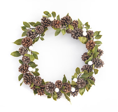 Top view of wreath with copy space. Winter holidays and Christmas celebration concept. Christmas wreath of white balls, laurel, bay leves and pine cones are isolated on white in flatlay style.