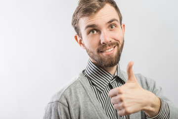 young man smiling and showing the thumbs up gesture.