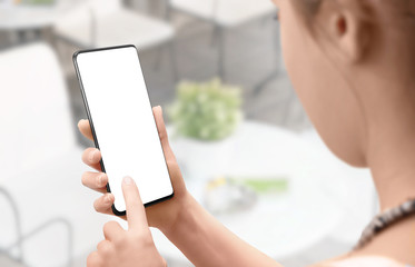 Girl use mobile phone with isolated screen for mockup. Coffee shop in background