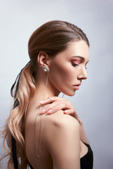 Beauty portrait of a woman with long hair, earrings in her ears and expensive jewelry on her hands