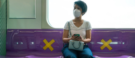 Banner photo of Asian female woman sitting in subway distance for one seat from other people a social distancing for protect coronavirus a new normal trend. Social distancing or new normal concepts