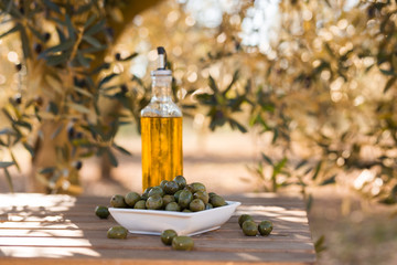 green olives and oil on table in olive grove