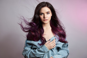 Portrait of a woman with bright colored flying hair, all shades of purple. Hair coloring, beautiful lips and makeup. Hair fluttering in the wind. Sexy girl with long hair styling