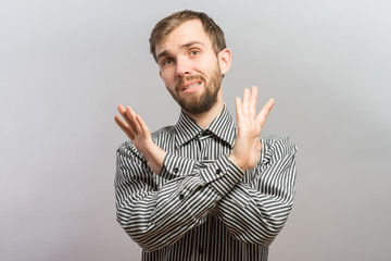 Serious and determined young man makes an X shape with his arms and hands. This could mean stop,...