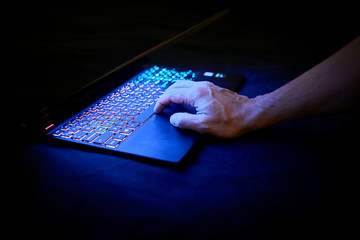 portatil encendito con teclas iluminadas, mano sobre las teclas