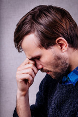 Fototapeta premium young man with a beard in blue sweater thinking with hand on face