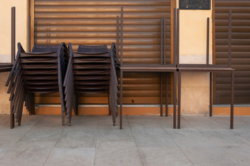 Brown plastic chairs stacked next to outdoor tables