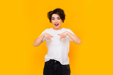 Young happy brunette woman with a short haircut in a white T-shirt on a yellow background. portrait...