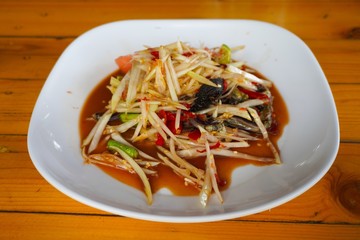 Papaya salad in white dish on wooden background
