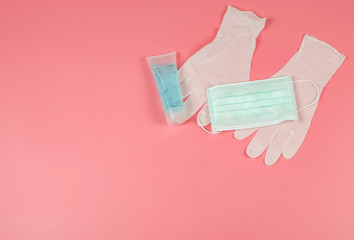 flat lay of hygienic disposable mask  above medical latex gloves on pink background. Coronavirus or covid19 protection concept.