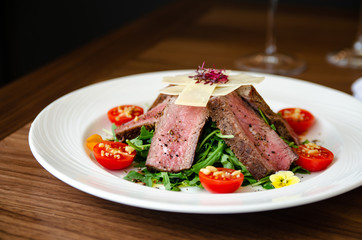 Cooked pork meat on top of rocket salad with cherry tomatoes