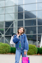 Happy brunette woman with shopping bags and cellphone enjoying in shopping. Shopping, lifestyle concept