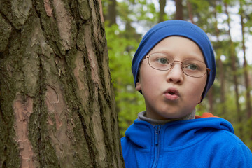 boy near pine tree in forest,boy in glasses stands near tree in forest