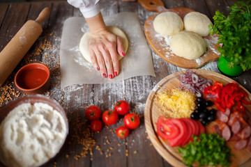 woman kneads the dough with hands while cooking pizza