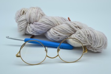 White ball of yarn with eyeglasses and a crochet hook