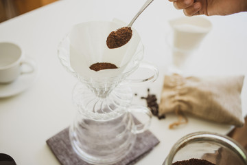Close up. roasted coffee on a stainless spoon, with professional of barista pour Roasted coffee for dripping hot coffee into the cup with equipment, tool brewing at kitchen home