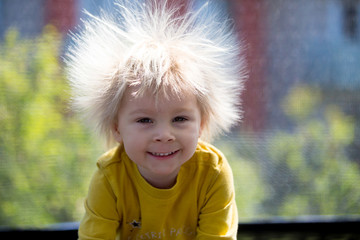 Cute little boy with static electric hair, having his funny portrait taken outdoors on trampoline