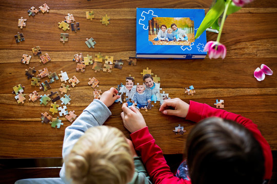 Two children, boys, assembling puzzle with their picture from an autumn forest, playing at home