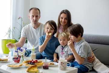 Happy family, having pancakes for breakfast, eating in living room, talking and lauging