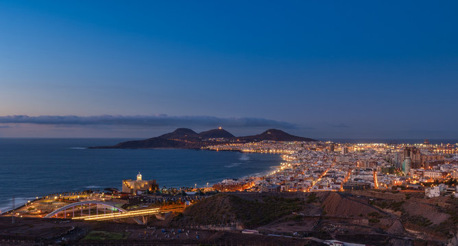 Vista panoramica de la ciudad de Las Palmas de Gran Canaria al anochecer con la playa de las Canteras y las montañas de La Isleta al fondo © magui RF