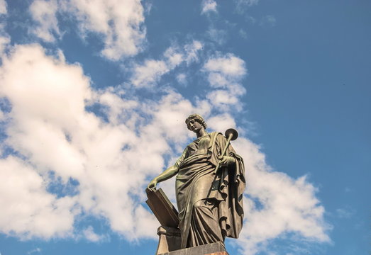 Ancient sculpture (18th century) of  ancient Greek muse of  history of Clio against  background of sky and clouds