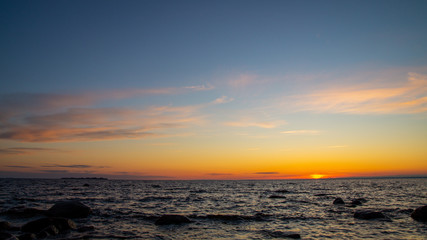 Fototapeta na wymiar Sunset on the shore of the sea, pink clouds, rocks.