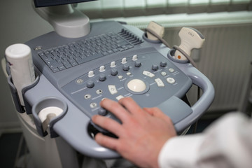 Obraz na płótnie Canvas Close up shot of technician operating an ultrasound machine at a clinic. 