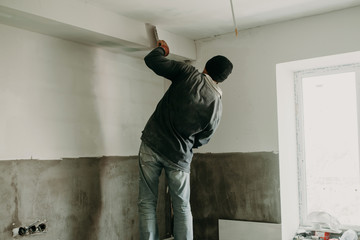 man putty ceiling repair in an apartment