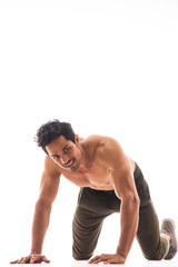 Man smiling and looking around while working out in front of a white background.
