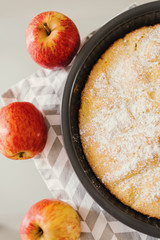Simple apple pie served with three whole apples of red and yellow color, top view
